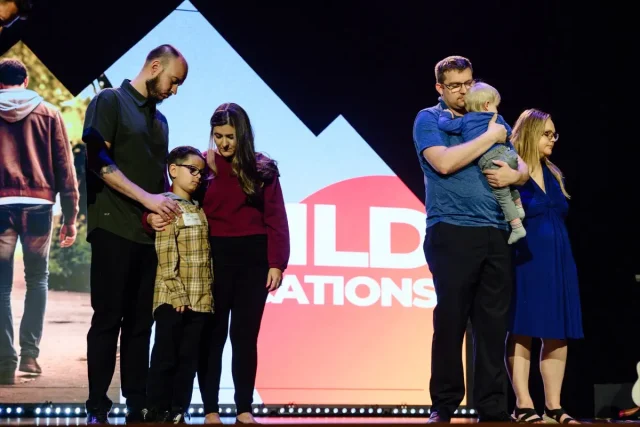two groups of families praying on a stage