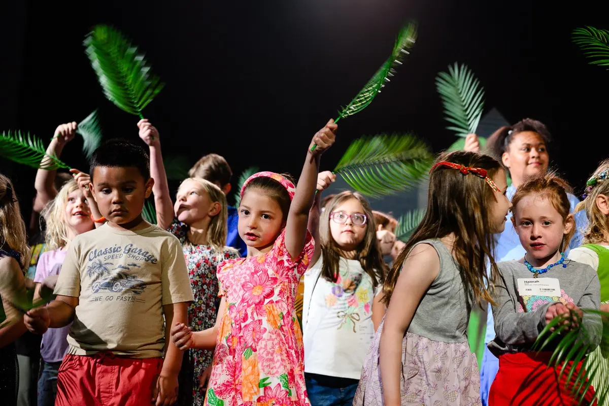 a group of kids waving palm fronds
