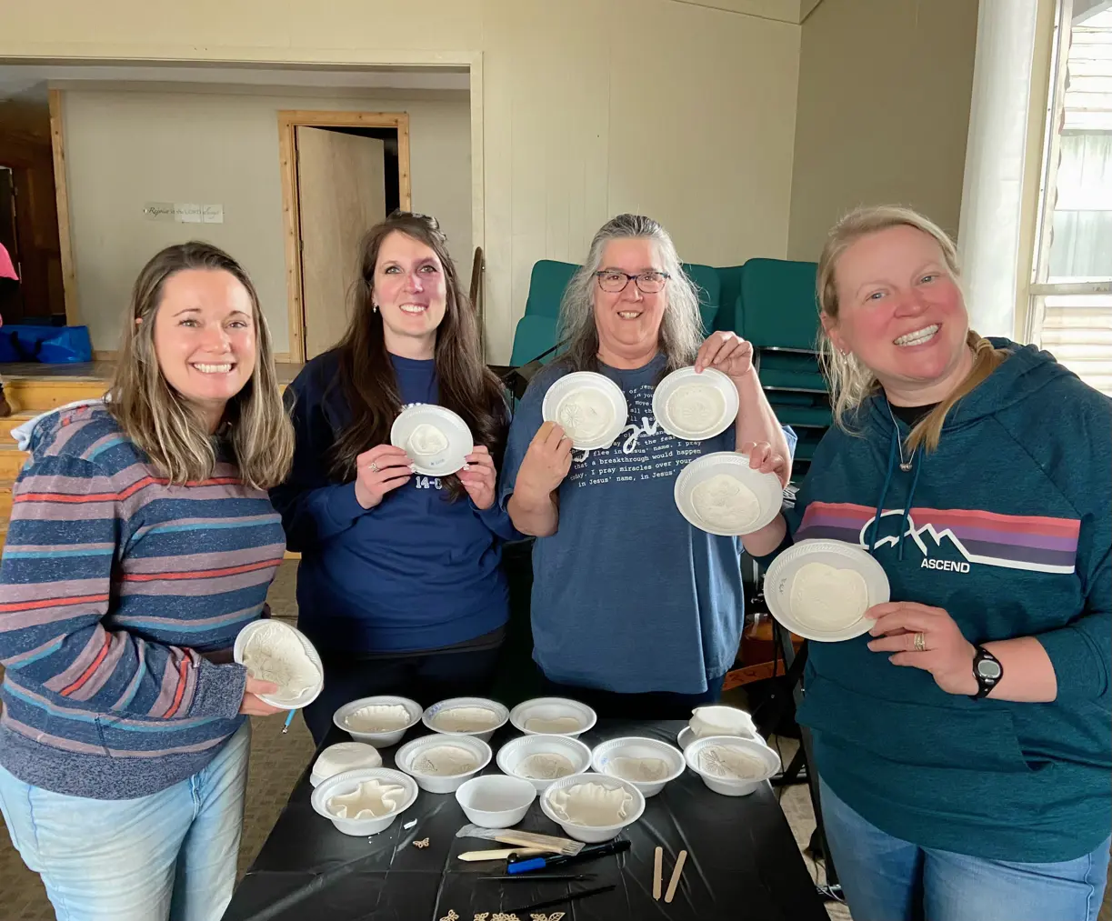 four women pose with crafts they made
