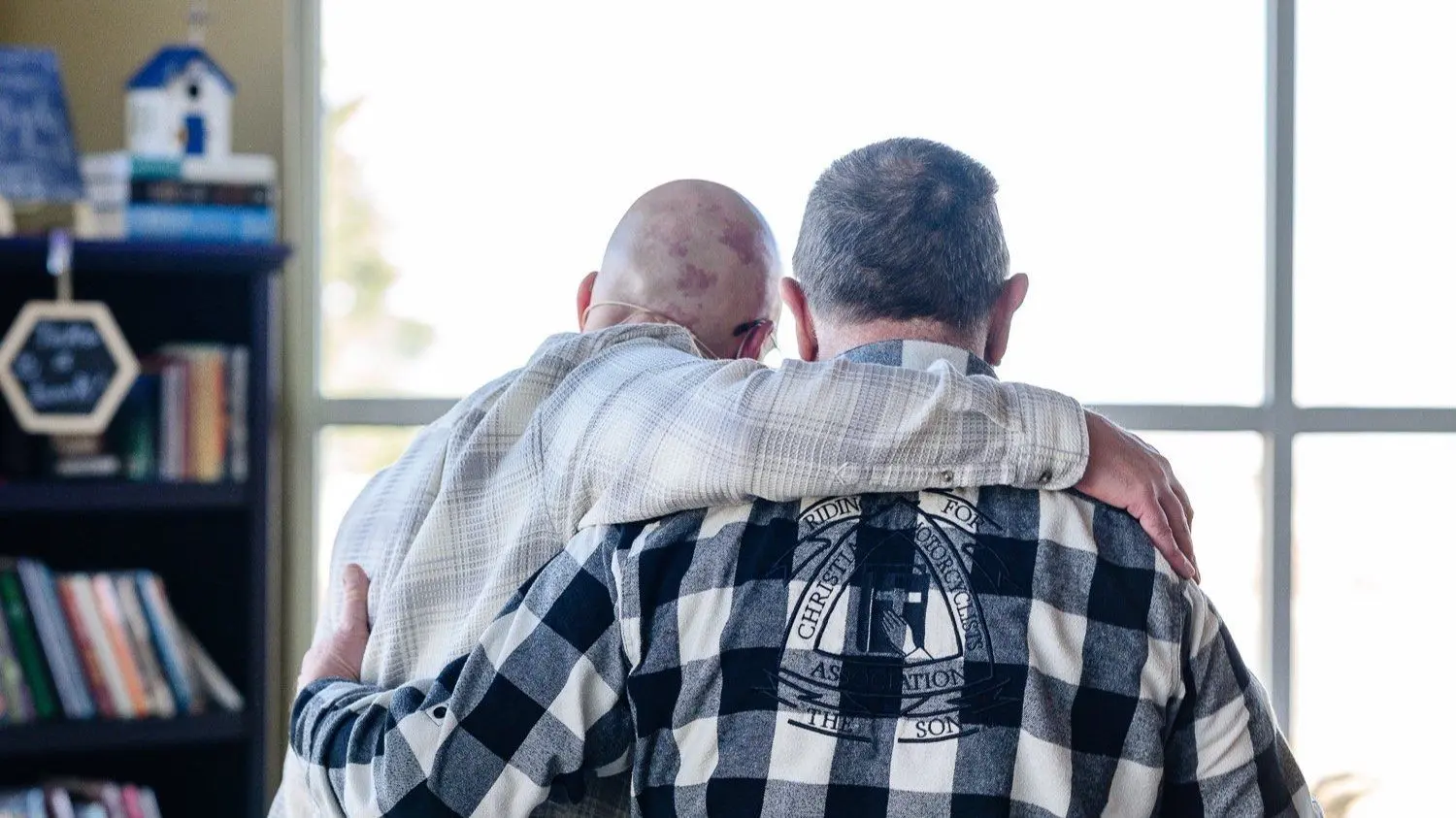 two men hugging, with their faces turned away