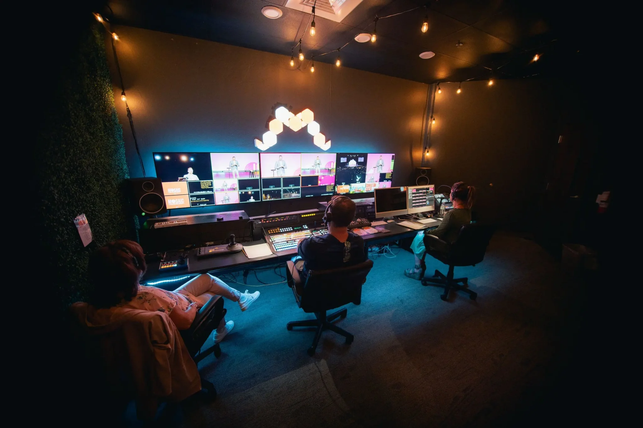 three production volunteers operating equipment in a video control room
