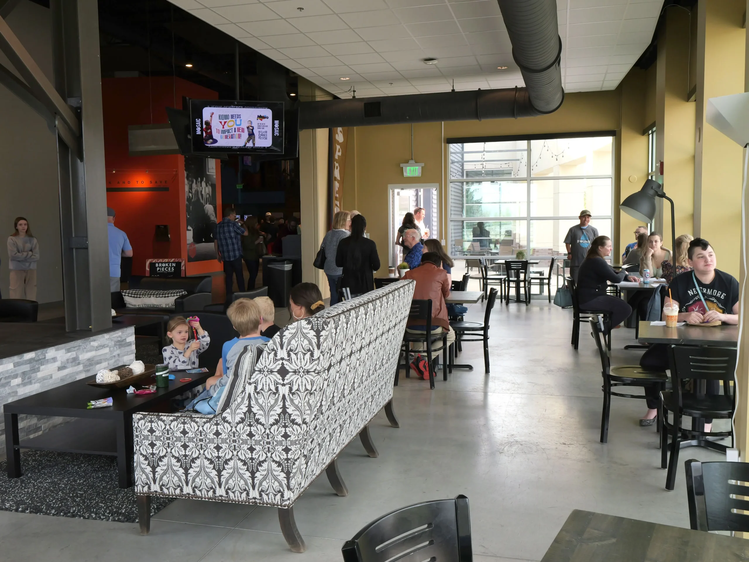 a large group of people sitting at tables and chairs in a cafe