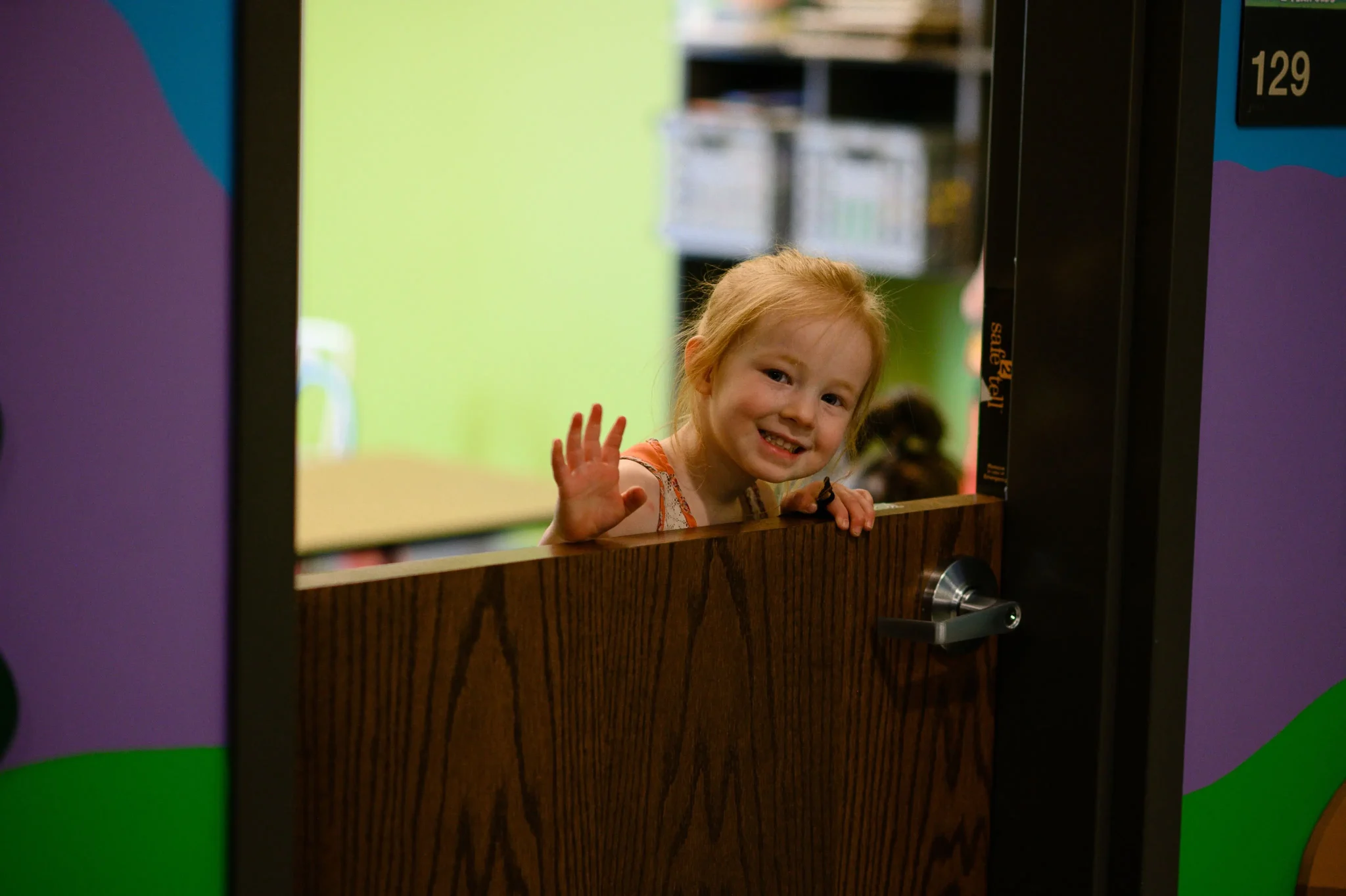 a young girl waving from behind a half-door