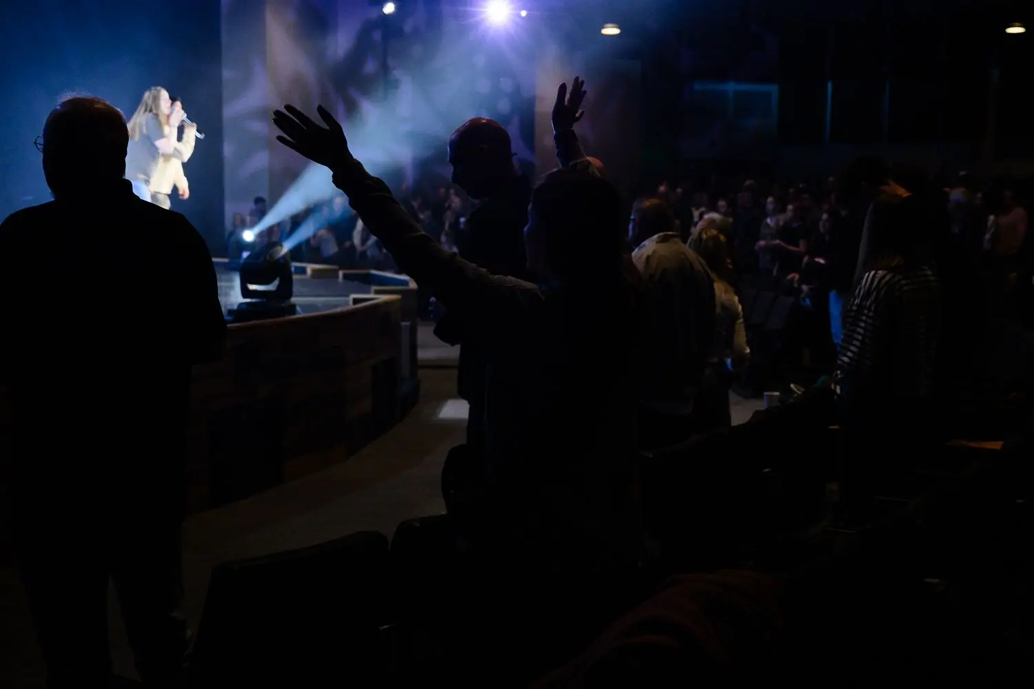 a woman with both arms raised during a worship service