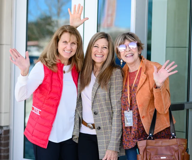 three women waving at the camera