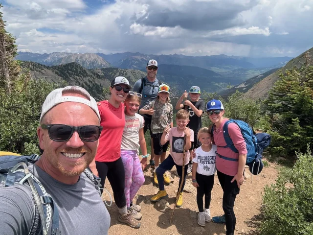 two families with children pose in front of a valley on a nature hike