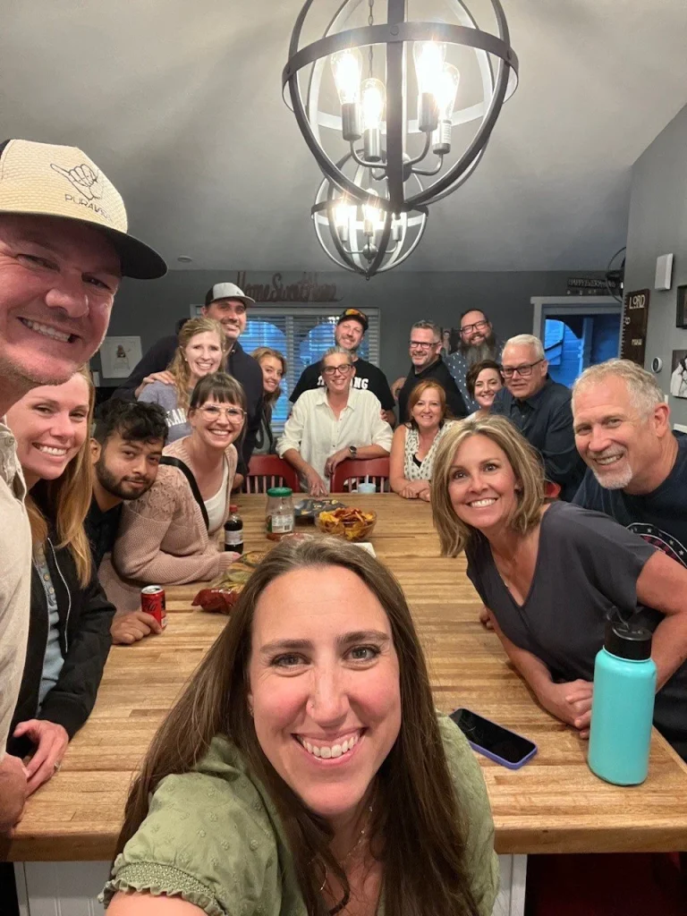 a large group of people posing around a table in a home