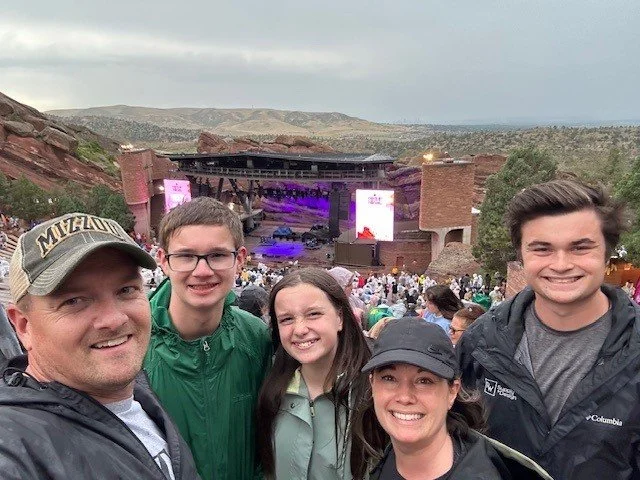 a family posing in front of Red Rocks amphitheater