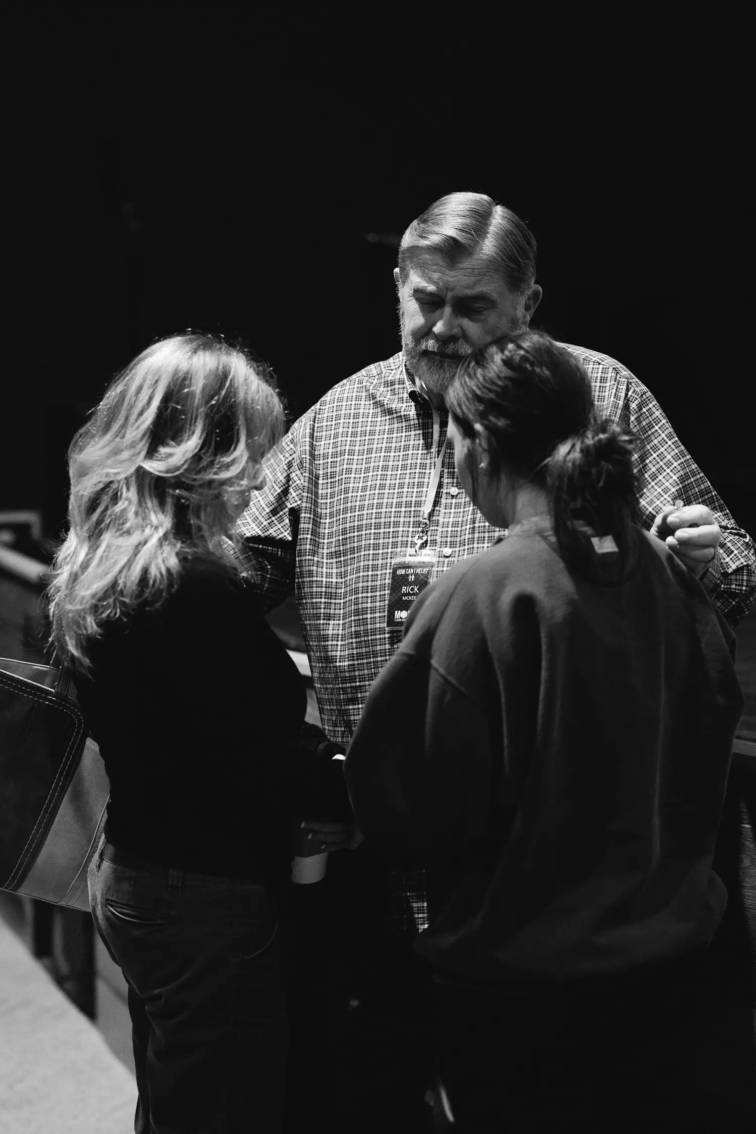 a pastor praying with two women
