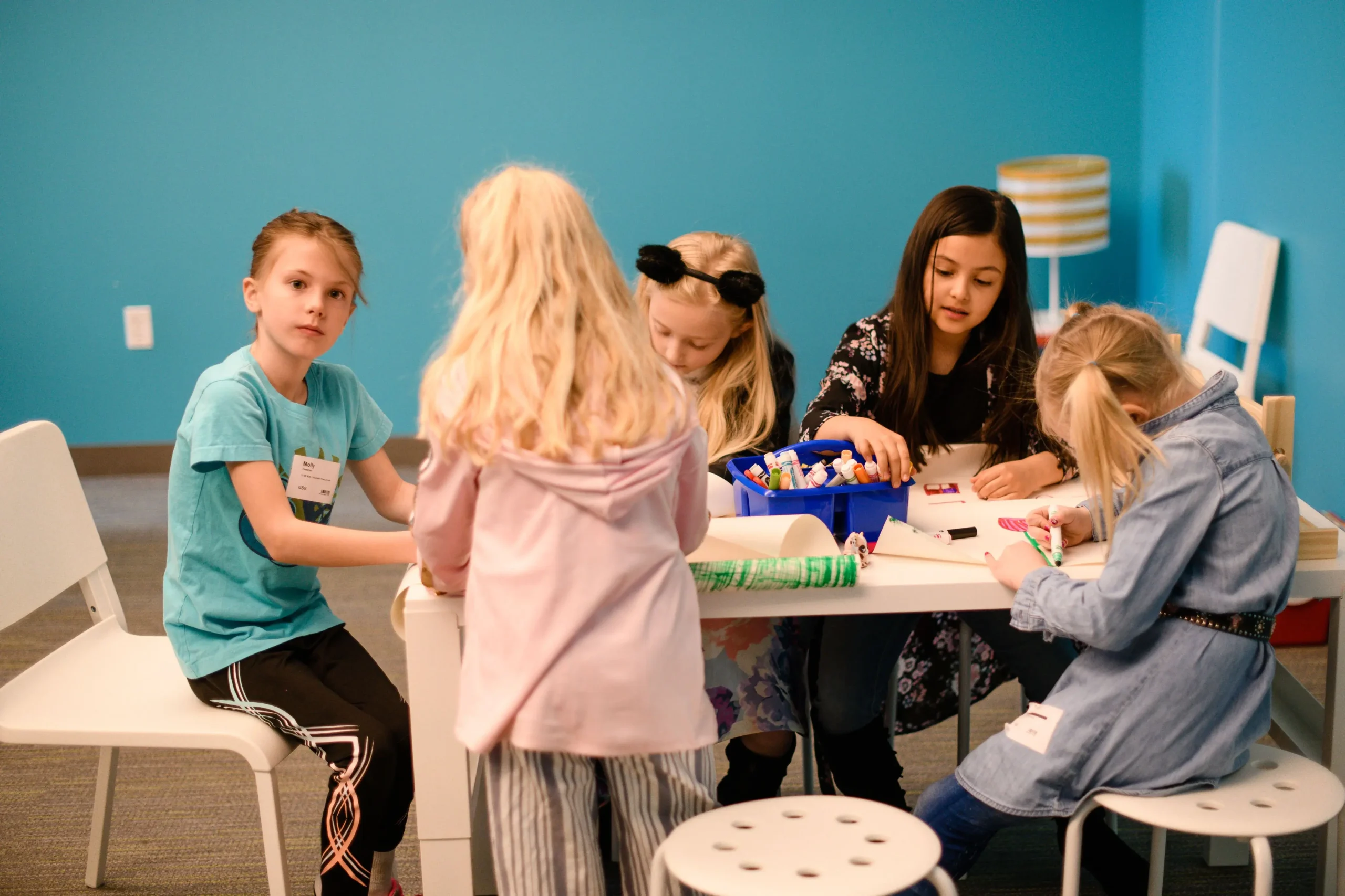 a group of girls doing a craft around a table