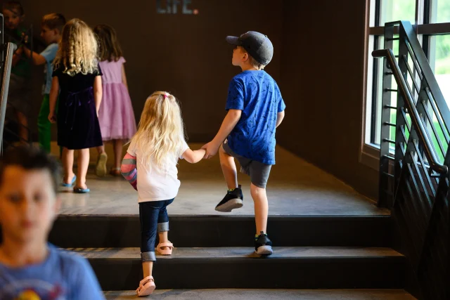 a boy and girl walking up stairs and holding hands