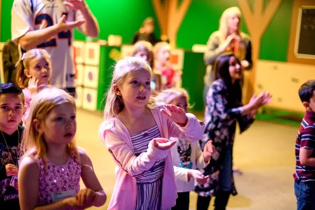 a group of kids doing hand motions for a song