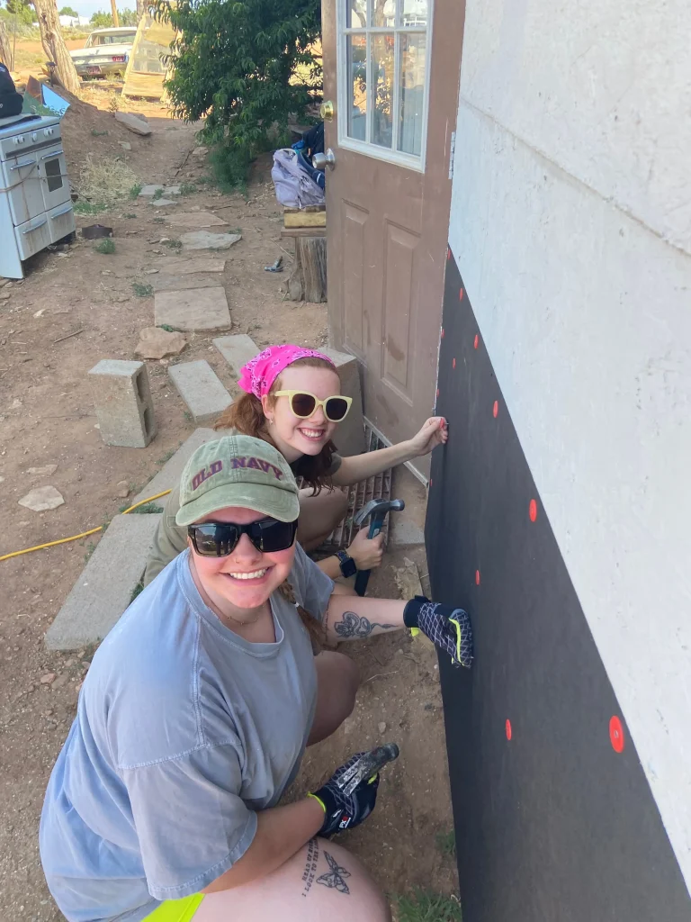 two young women repairing a house wall